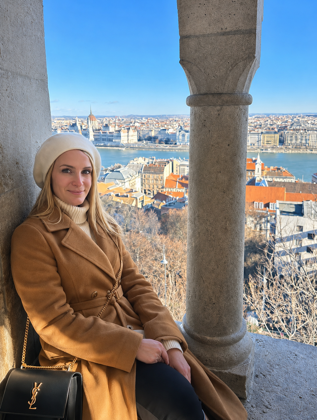 Dorina con cappotto color cammello davanti a una vista panoramica di Budapest