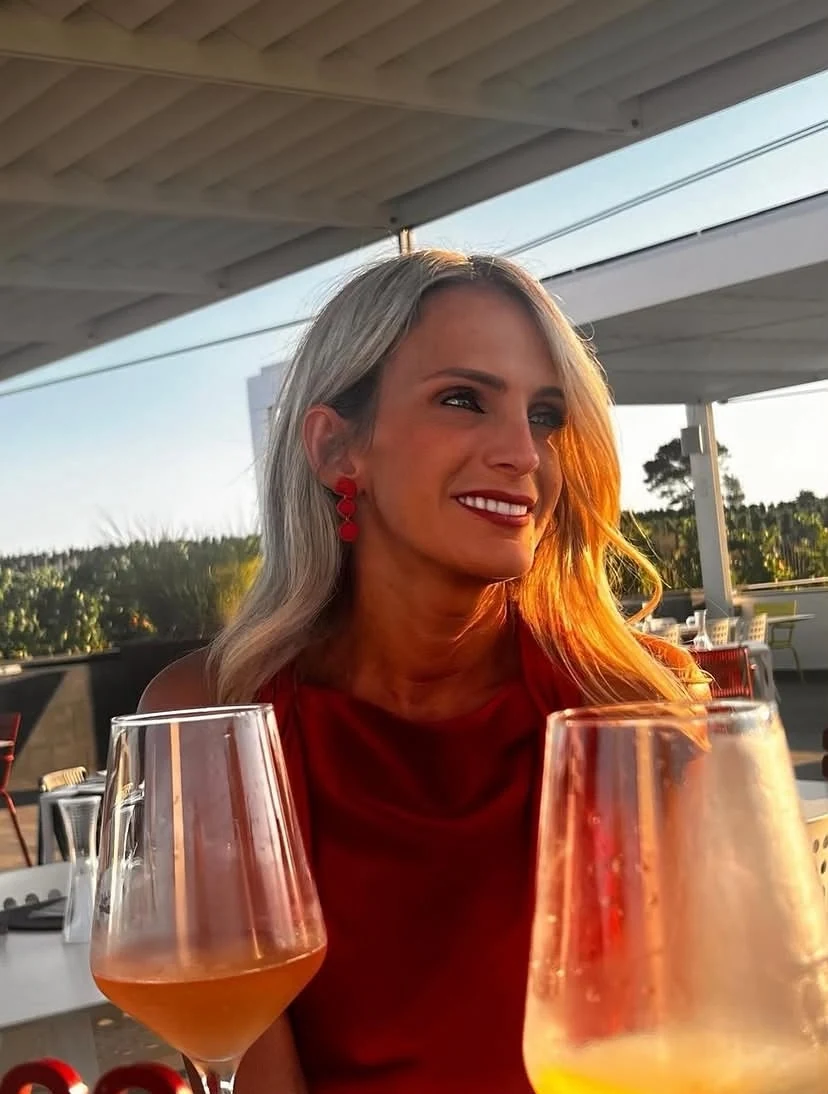 Dorina sorridente in abito rosso durante un aperitivo al tramonto
